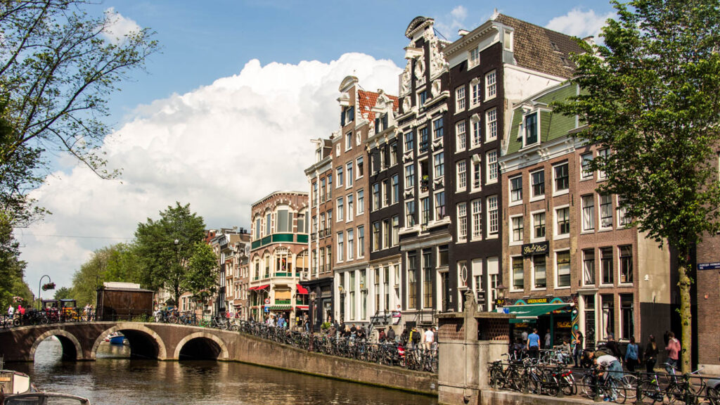 Canal em Amsterdam com ponte e fileira de casas estreitas de arquitetura típica neerlandesa
