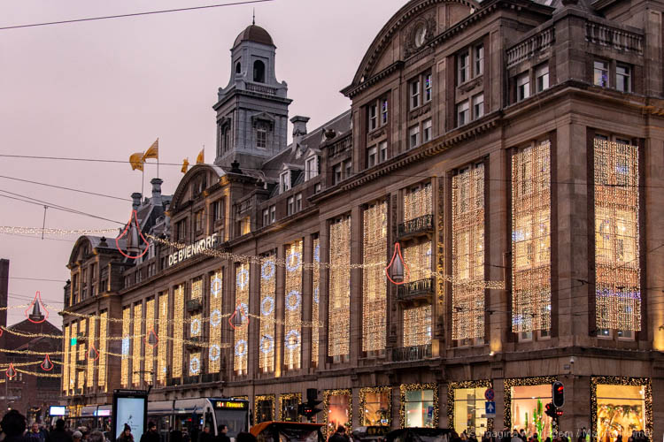 Fachada iluminada da loja de departamentos De Bijenkorf na Praça Dam, em Amsterdam