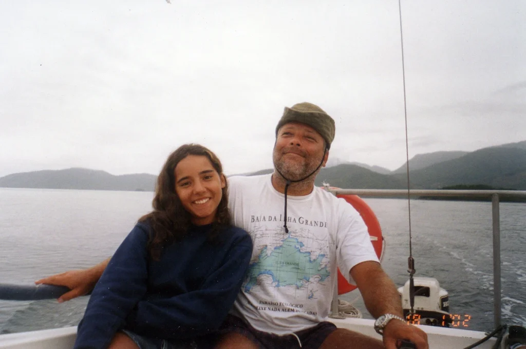 Foto antiga de Marina ainda criança em um veleiro com o pai